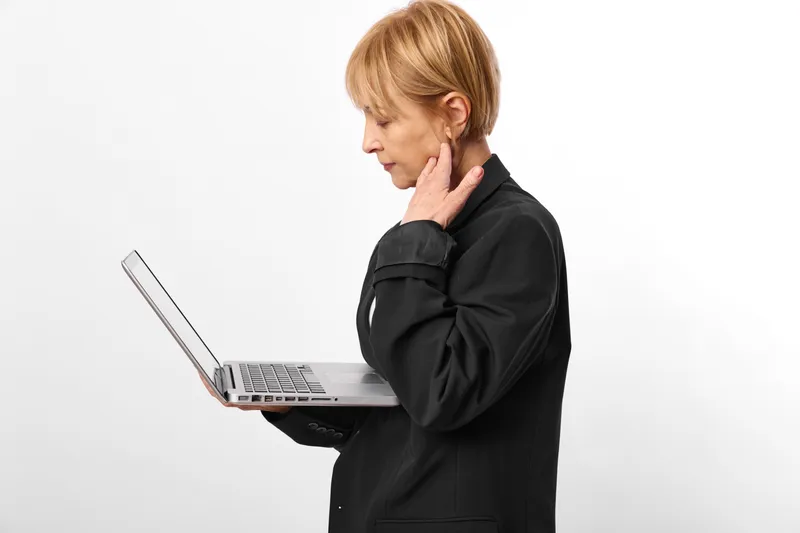 Woman with laptop, hand on neck, stress fatigue in business office, headache tension, concentration with technology, modern studio white background, soft light