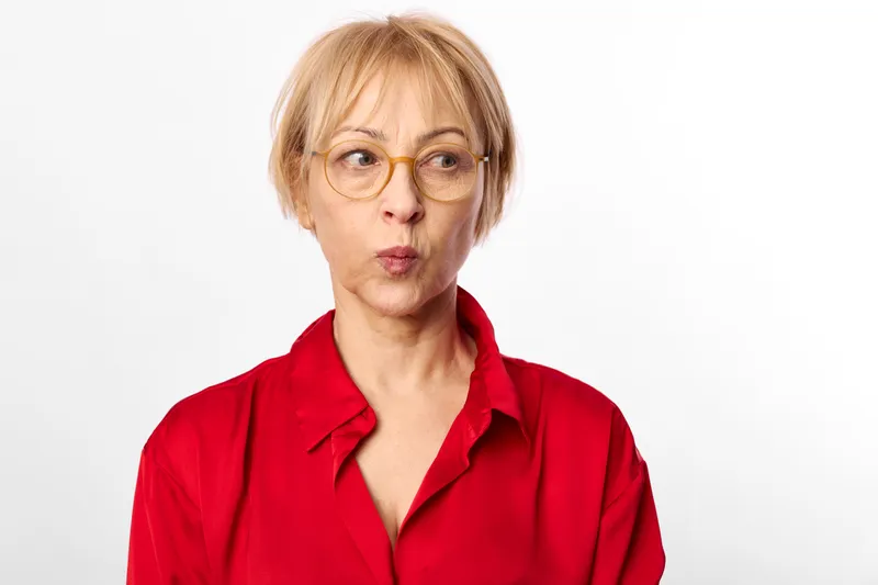 Woman portrait with glasses and red blouse in a studio, blonde short hair, neutral background, direct gaze, calm serious expression, clean lighting, minimal style