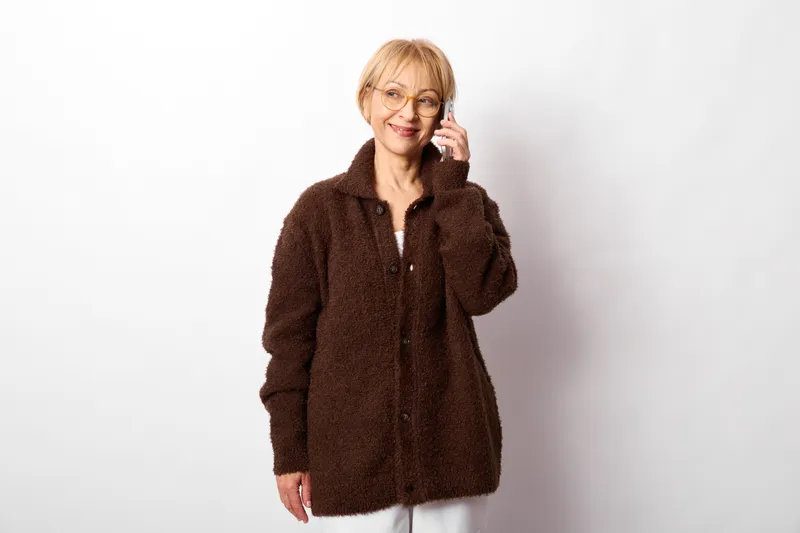 Woman fur coat smiling portrait studio blonde white background casual look indoors soft light relaxed pose touching hair clean neutral backdrop full body framing for style shot