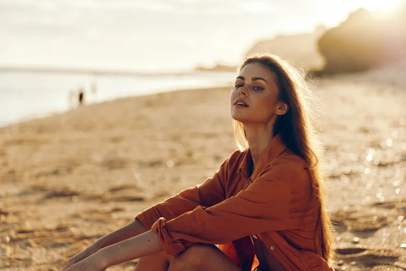 Woman beach sunset sea sunlight relax portrait nature summer mindfulness Calm female model sits on shoreline beside waves in warm jacket at golden hour, peaceful contemplative escape by ocean
