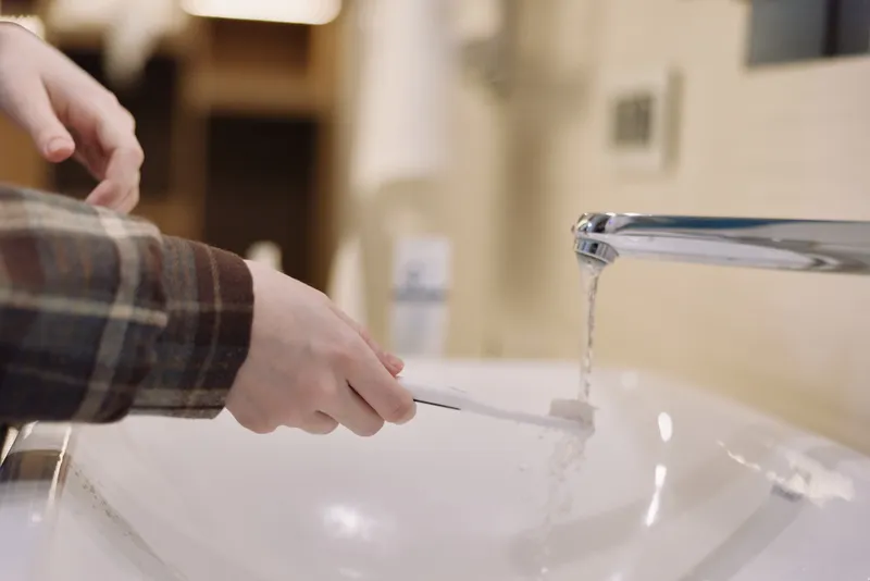 Close up of hands rinsing at a sink with running water, showcasing daily hygiene and grooming in a clean bathroom setting for health awareness