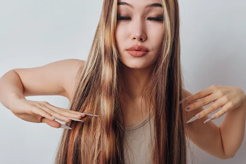 Woman with long shiny hair combing strands in closeup for haircare, grooming and beauty routine. Female model with closed eyes showing healthy hair and natural texture.