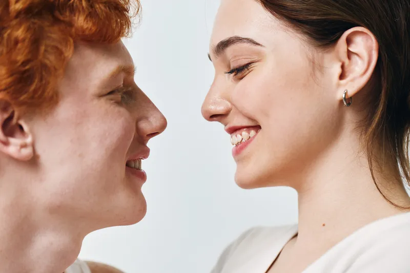 Young couple smiling and looking at each other with happiness and affection in closeup portrait. Man and woman enjoying moment with love and connection on white background.