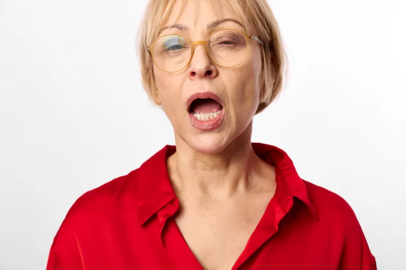 woman, glasses, surprised, shouting, mouth open, red shirt, white background, portrait, blonde hair, eyewear, studio lighting, shocked emotion