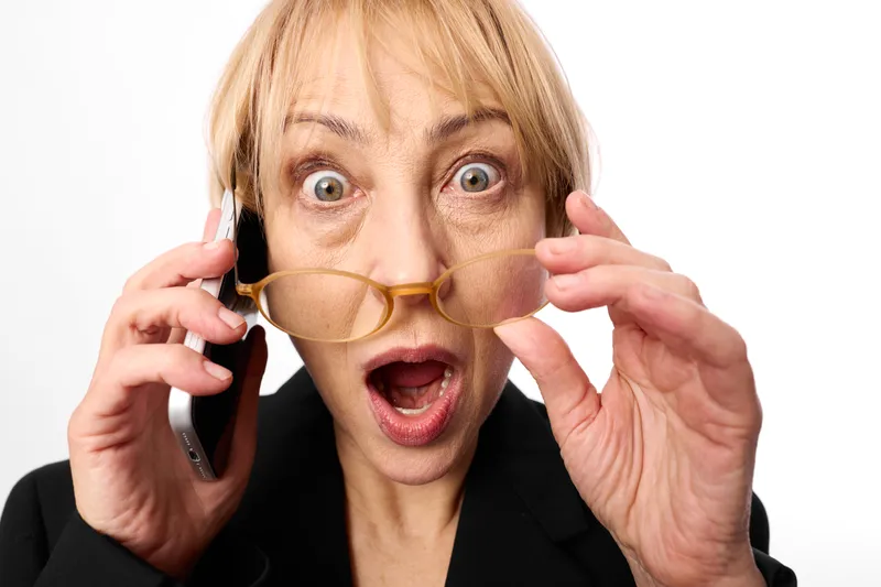Woman surprised on phone, holding novelty glasses, prank fun communication party mood, facial expression with open mouth, isolated on white background, closeup