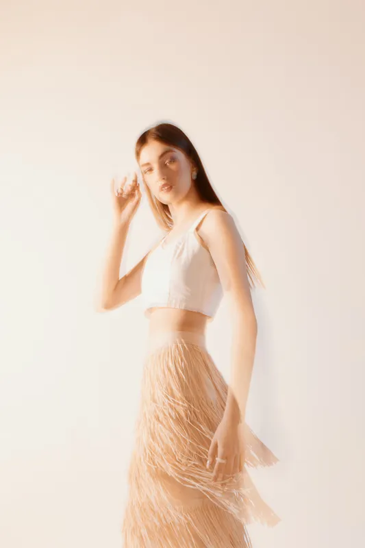 Young woman in a stylish outfit poses with soft motion blur effect on a light background. Concept of beauty, fashion, elegance, and modern lifestyle for editorial use.