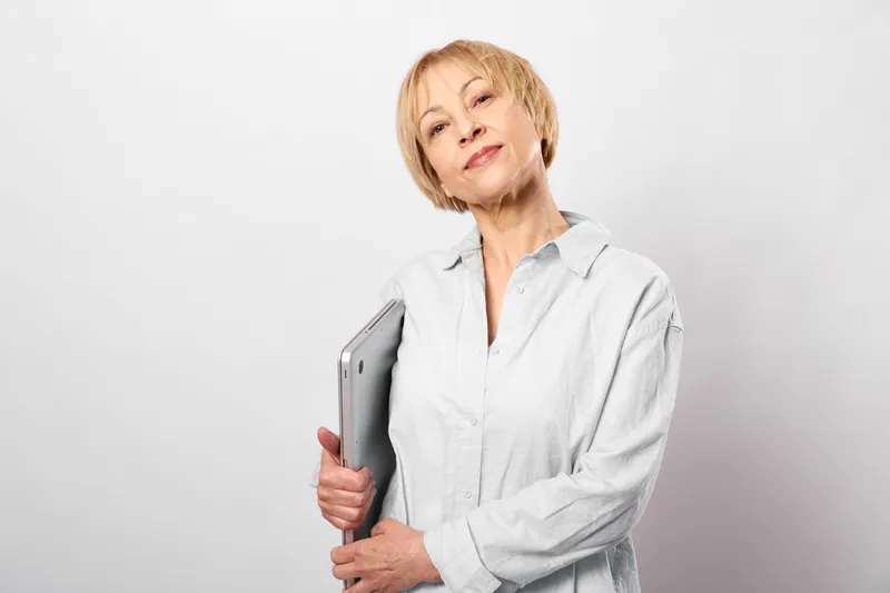 Senior doctor holding a tablet in a white coat on plain light background, calm confident pose, telemedicine for telehealth, digital health, healthcare, medical technology