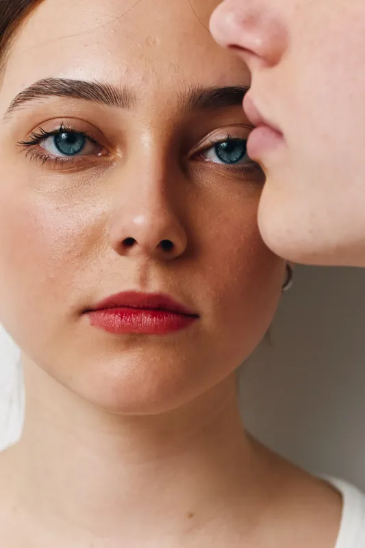 Portrait of young woman with blue eyes and red lips, close up face and natural skin texture with focus on facial expression and beauty in soft light.