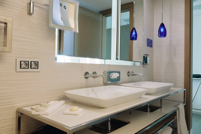 Bathroom scene featuring a modern vanity with a doublesink, clean lines and bright lighting. An interior design inspired layout, hotelbathroom style, with reflective surfaces and organized fixtures.