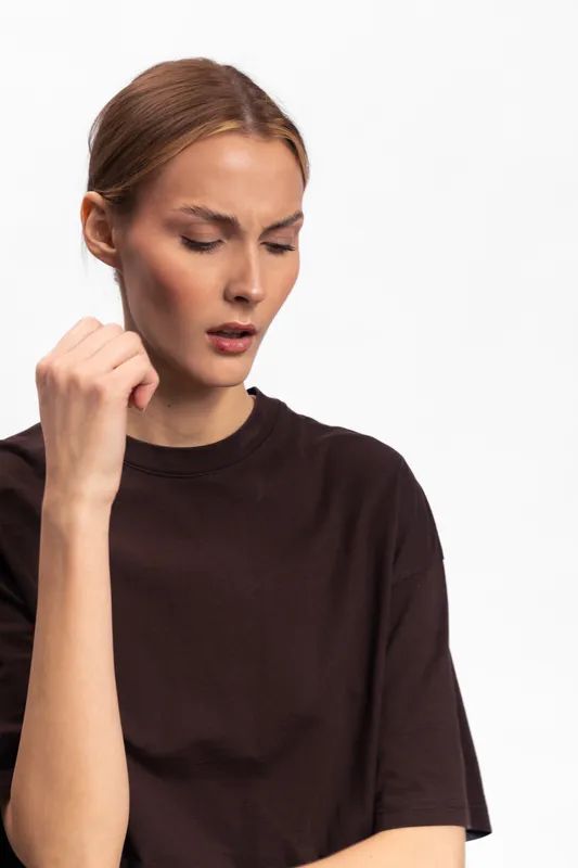 Young woman in dark shirt with closed eyes and slightly open mouth shows discomfort or pain, isolated on white. Concept for illness, headache, or emotional distress in studio.