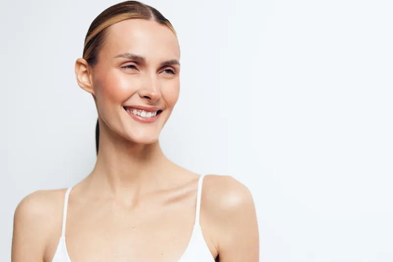 Smiling woman portrait of young adult with natural beauty, skincare care and wellness concept, clean light background, friendly expression, close up face, copy space