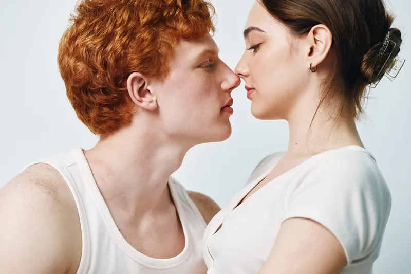 Couple, love, romance and intimacy with young man and woman about to kiss in white studio. Closeup, affection and relationship with tender moment for connection and feelings.