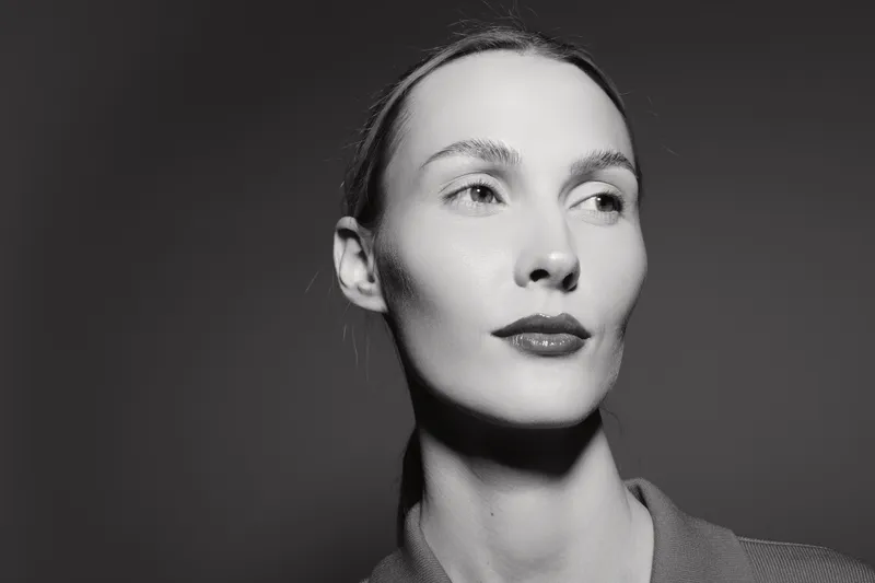 Portrait of a young Caucasian woman with fair skin looking sideways in black and white studio lighting. Concept of elegance, beauty, and minimalism in photography.