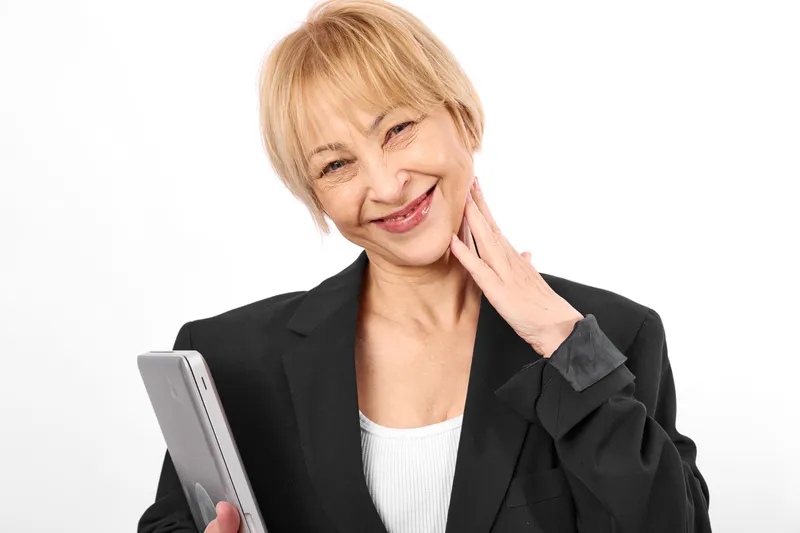 Elderly woman holding smartphone, smiling with hand on neck, pain relief and comfort, healthcare senior communication concept, isolated on white background