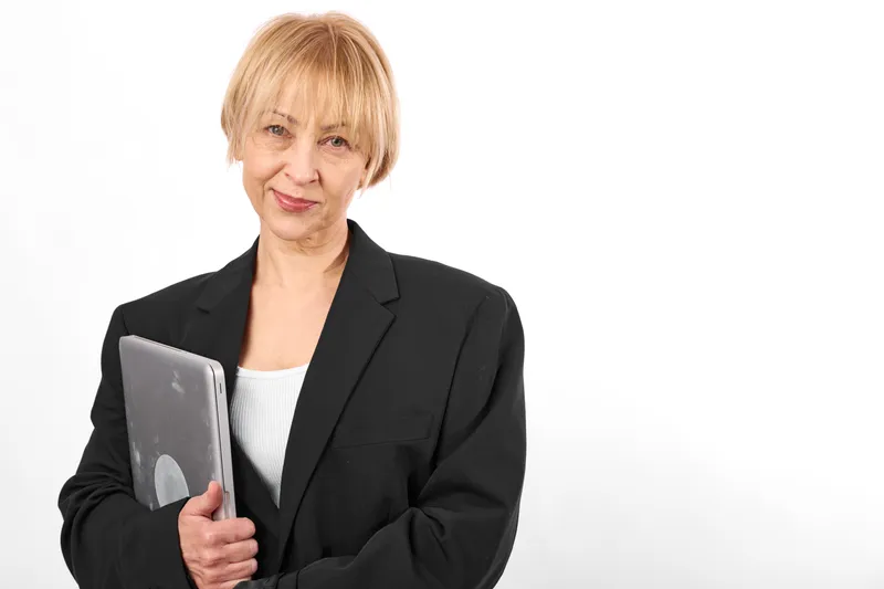 Business woman portrait, senior professional in dark suit holding a tablet, calm confident expression, studio white background, corporate technology and work concept