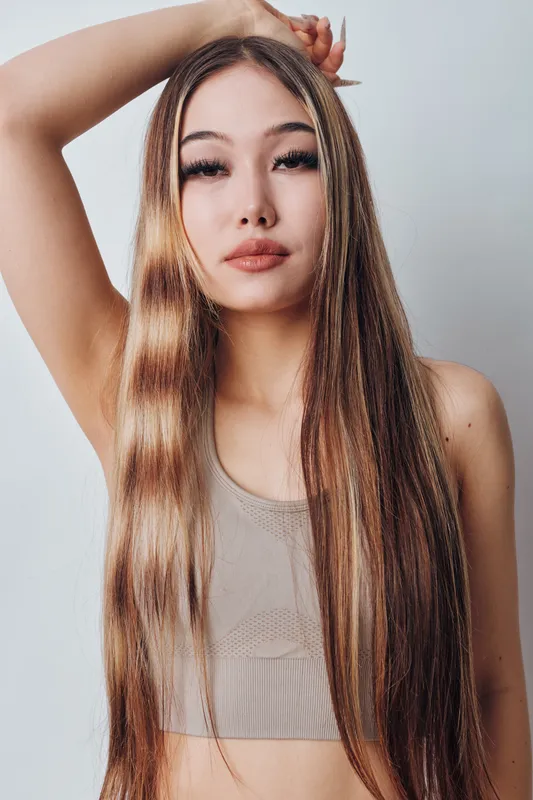 Young woman with long brown hair and braids posing in sleeveless top against white background. Beauty, fashion, portrait and confidence in casual style with natural makeup.
