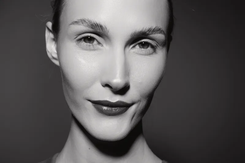 Close-up portrait of a young white woman with clear skin and subtle makeup in black and white. Concept for beauty, skincare, and natural expression.