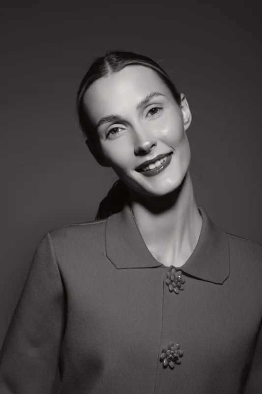Portrait of a happy Caucasian woman with light skin smiling in black and white. Studio lighting highlights facial features and elegant clothing.
