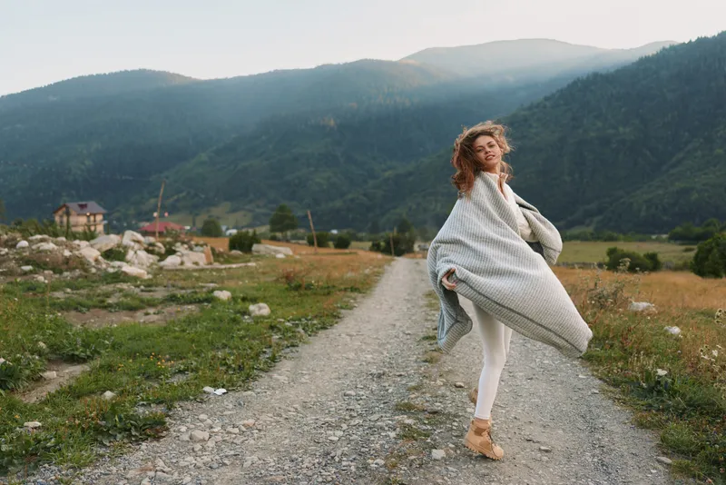 Smiling woman twirls on a gravel path in a mountain valley, embracing outdoor life and wellness, relaxed mood with soft natural light, carefree vibe Bright mood today.