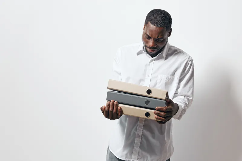 African American man with dark skin holding office folders in white shirt standing against white background for business, work, organization and paperwork concept.
