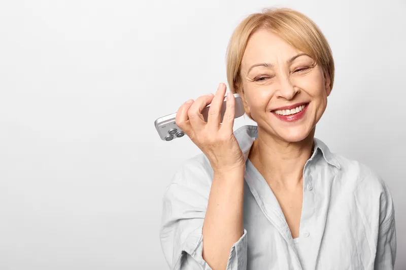 Elderly woman smiling, smartphone online payment, holds credit card while calling, secure communication for banking, modern digital transaction, isolated on white background, copy space