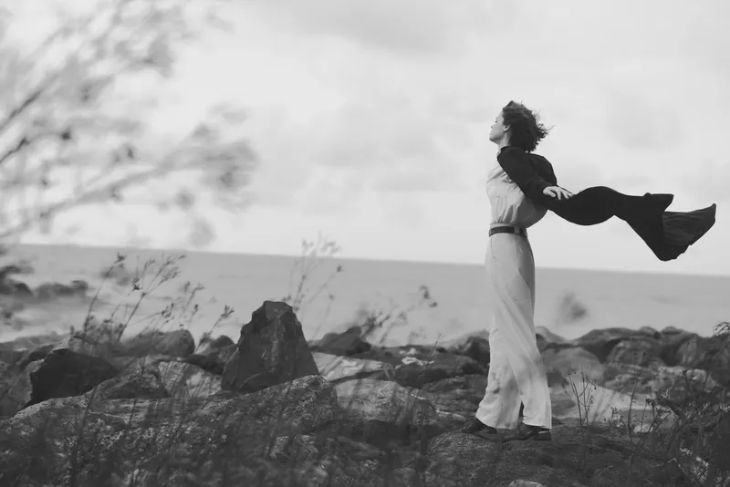 Love and embrace in a seascape, a couple lifting each other in a tender moment by rocks and wind, monochrome mood with open horizon