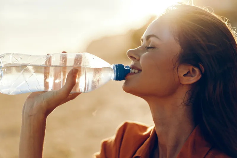 Woman drinking water, hydration, health outdoors, summer closeup, sunlight glow, wellness concept, female adult profile sipping bottle, refreshing clean beverage, natural lifestyle, photo