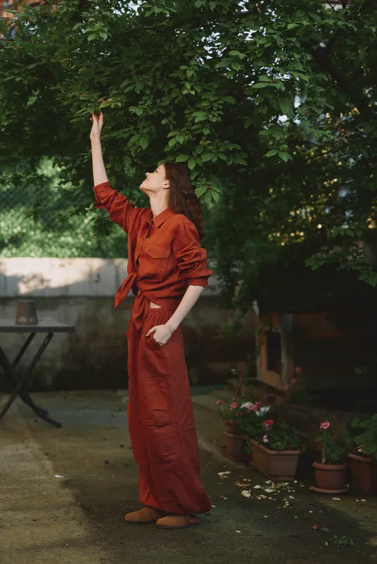 Woman lifestyle outdoor dress garden pose reach in a candid moment with natural light, capturing a warm, relaxed mood