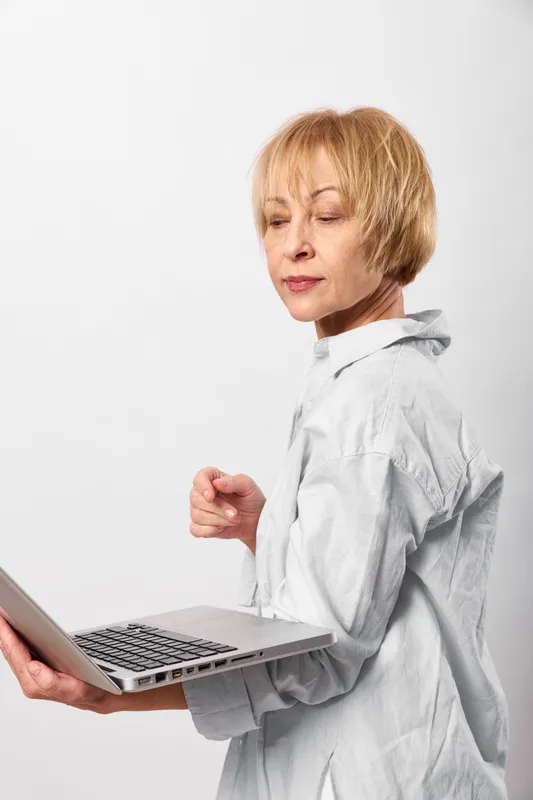 Woman doctor in laboratory coat holds a laptop, tired with closed eyes and tense hands, stressed and worried, suggesting illness and burnout for telemedicine in healthcare on clean white background