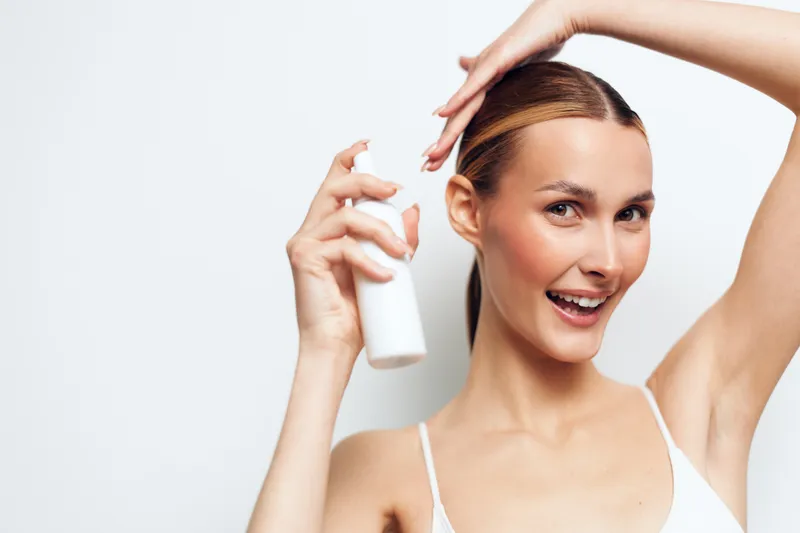 Smiling woman applies hair spray for beauty, skincare personal care, holding spray bottle and adjusting hairstyle, on clean white background, close up portrait, minimal style.
