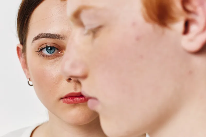 Woman with earrings looks at man in closeup portrait for relationship, communication and emotion. Couple with serious expression and focus on female face for intimacy and connection.