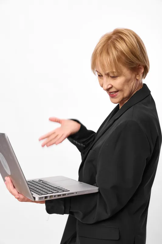 Woman in business suit, using laptop, isolated on white background, office technology work, looking down with concentration, hands near keyboard, calm professional moment