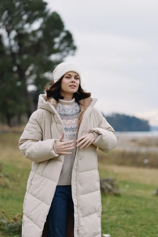 Winter coat, outdoor portrait, cold weather, woman, beanie, cozy outfit in natural park by lake, calm mood, soft light and gentle breeze.