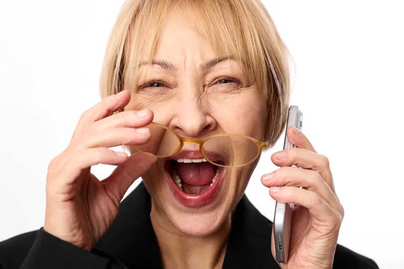 Woman phone call communication business blonde laughing portrait, studio closeup on white background, holding landline handset and smartphone, shouting smiling