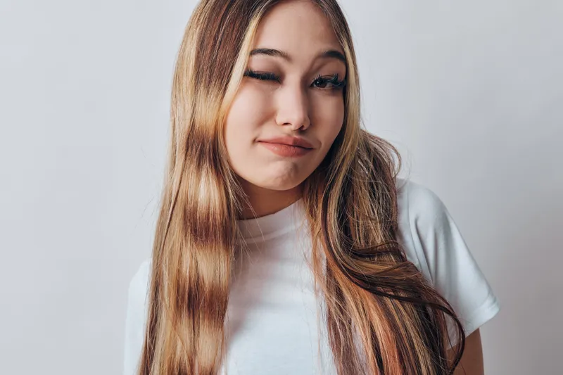 Young woman with long hair winking face emotion on white background. Beauty, casual, portrait, female, expression, hair, hairstyle, indoors, studio, happiness.