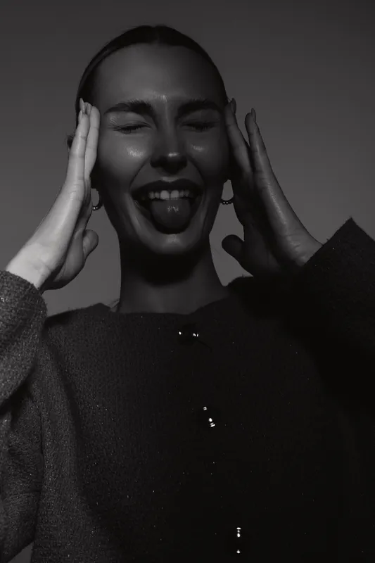 Portrait of a happy smiling young woman with dark skin and black hair pulling a funny face with closed eyes and tongue out. Concept of joy, playfulness, and natural beauty.