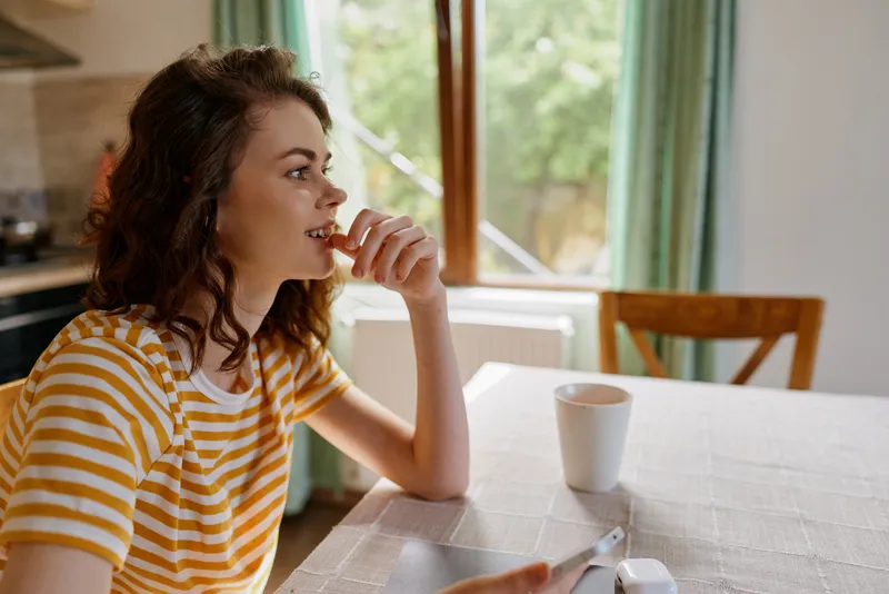 woman lifestyle home coffee table window light contemplation casual morning, a candid scene of a woman relaxing at home with coffee by a sunny window, capturing a quiet, everyday moment