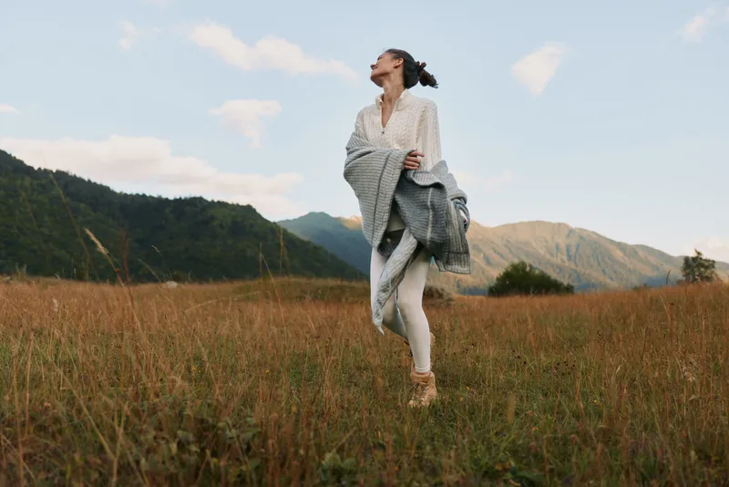 A young woman runner moves across a golden field in the countryside, wind in her hair, basking in freedom and a carefree outdoor moment.