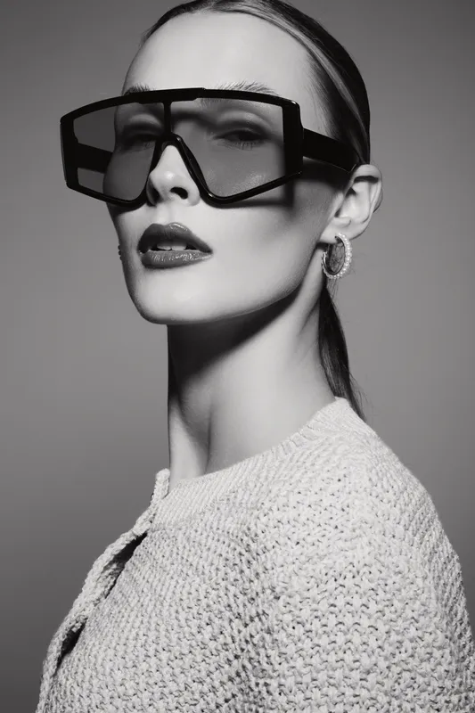 Portrait of a fair skinned Caucasian woman wearing oversized sunglasses and earrings. Black and white studio photo with fashion and style concept.