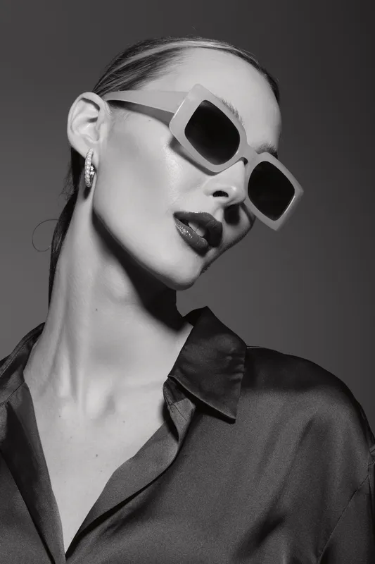 Elegant slender Caucasian woman with pale skin wearing large sunglasses and dark lipstick in studio. Fashion concept.