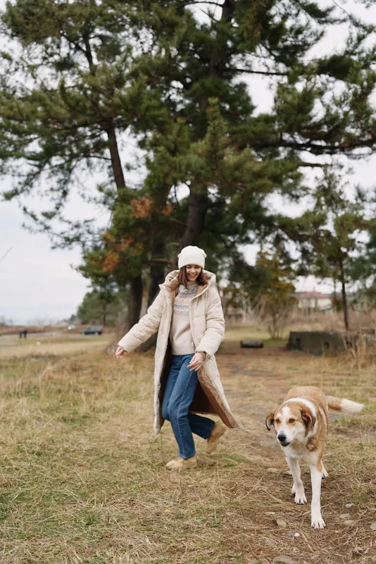 woman dog park outdoor walking coat in autumn, a serene moment with leash and trees in a spacious park setting, capturing casual companionship