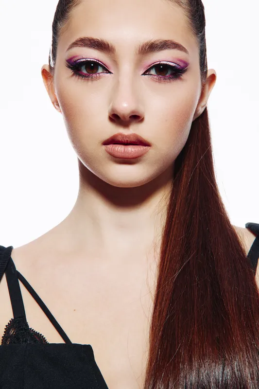 Close-up portrait of a young woman with vibrant creative makeup and smooth long hair. High fashion styling on a white background. Concept for beauty, fashion, creativity, editorial.