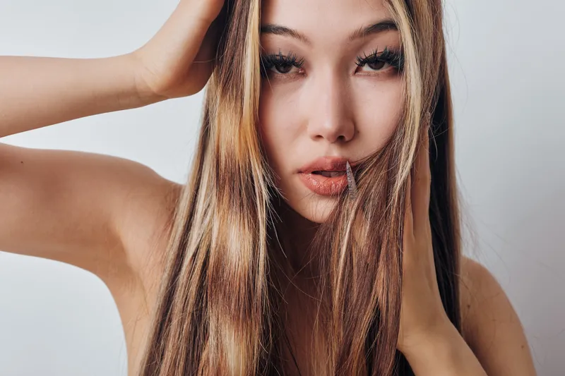 Young woman with long straight hair posing in closeup portrait, beauty, fashion, female model with natural makeup and clear skin on neutral background in studio lighting.