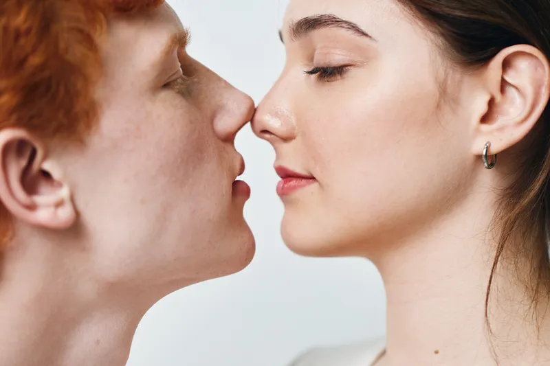 Couple with close faces and eyes closed in loving moment, intimate connection, romance with gentle touch and peaceful expressions on light background, affection and trust.