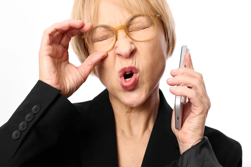 Business woman with sunglasses holding smartphone looks surprised, open mouth gesture, fashion portrait, office style, studio white background, isolated adult female