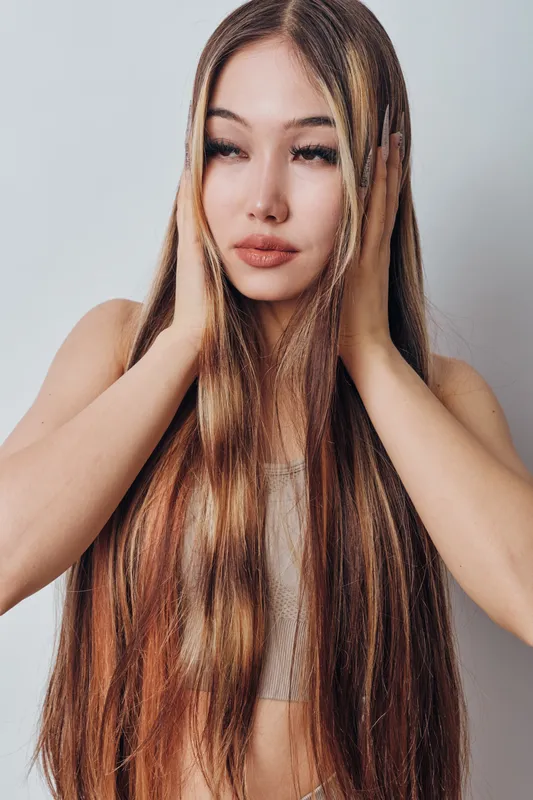 Young woman with long straight hair and light makeup posing with hands near face on neutral background. Beauty, fashion, portrait and hairstyle with natural look for model and lifestyle.