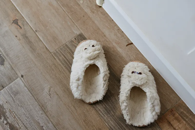 Cozy slippers sit on a wooden floor in a bright home setting, inviting a relaxed morning routine, gentle self care and comfort after a long day in a calm lifestyle scene