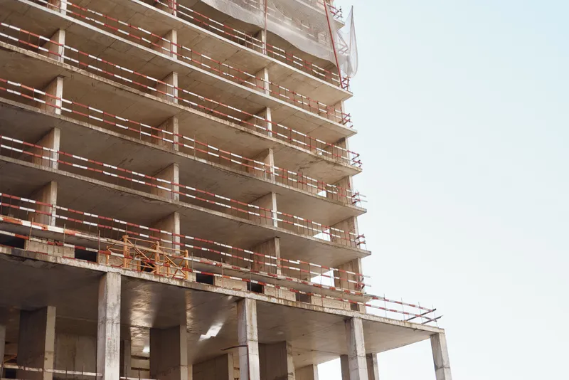 Construction site with a multi story concrete building under progress and scaffolding on each level bright daylight captures urban development and work in progress