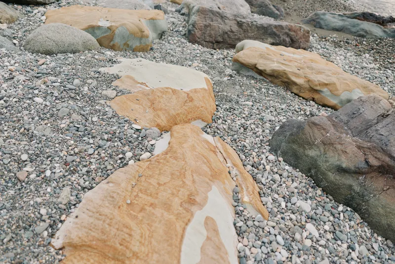 Close-up of natural rocks and pebbles on a beach shore showing textured stones in various shapes and colors. Concept of nature, geology, and outdoor environment.