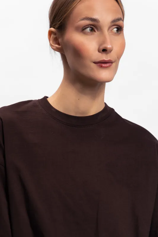 Portrait of a young woman in a dark sweater looking sideways with a neutral expression on a white background. Concept for fashion, style, and casual wear.